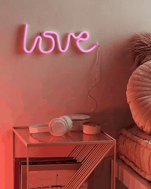 a neon sign that says love hangs on a wall above a nightstand