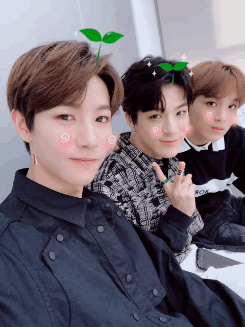 three young men are posing for a picture and one of them has a plant on his head