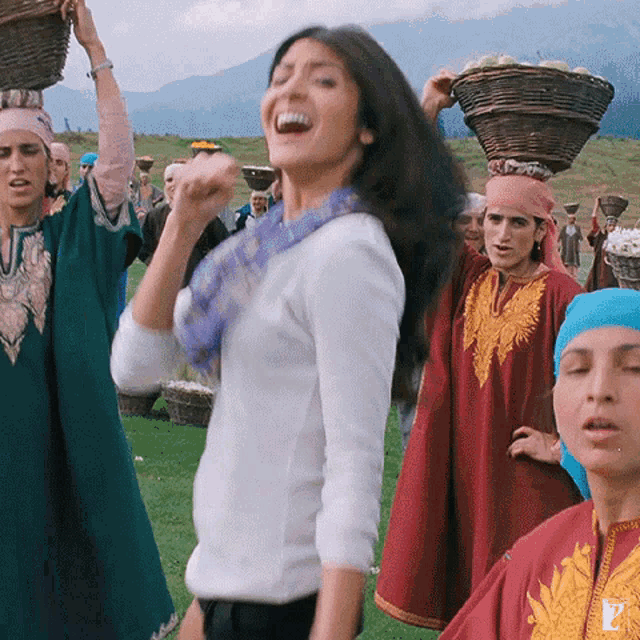 a group of women are carrying baskets on their heads and one of them is wearing a scarf with the letter p on it