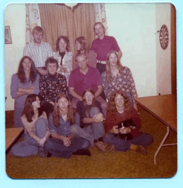 a group of people are posing for a picture in a room with a dart board in the background