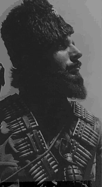 a black and white photo of a man with a beard holding a gun