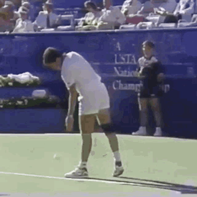 a man is standing on a tennis court in front of a sign that says a us national championship .