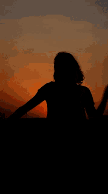 a silhouette of a person watching the sun set