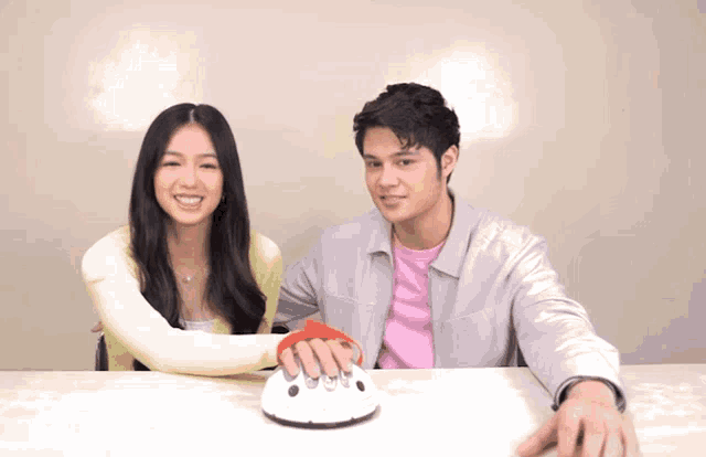 a man and a woman are sitting at a table with a cake in front of them that says ' i love you '