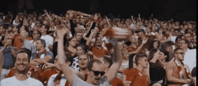 a crowd of people in a stadium with a man wearing sunglasses holding a scarf that says ' liverpool '