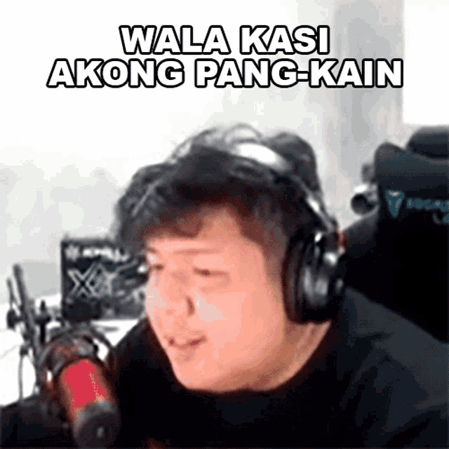 a man wearing headphones is sitting in front of a microphone and says wala kasi akong pang-kain