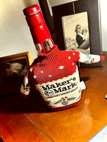 a bottle of maker 's mark kentucky whiskey with a red sweater on it