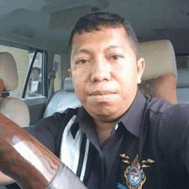 a man is sitting in the driver 's seat of a car and taking a selfie .