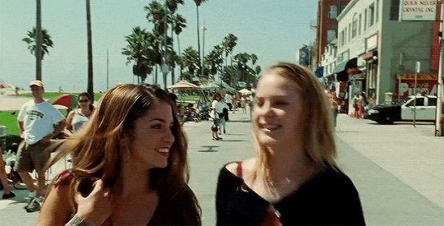 two women are walking down a sidewalk in front of a store that says quicksilver crystal inc.