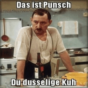 a man standing in a kitchen with a bottle of wine and the words das ist punsch du dusselige kuh