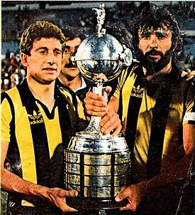 a man in a yellow and black adidas shirt holds a large trophy