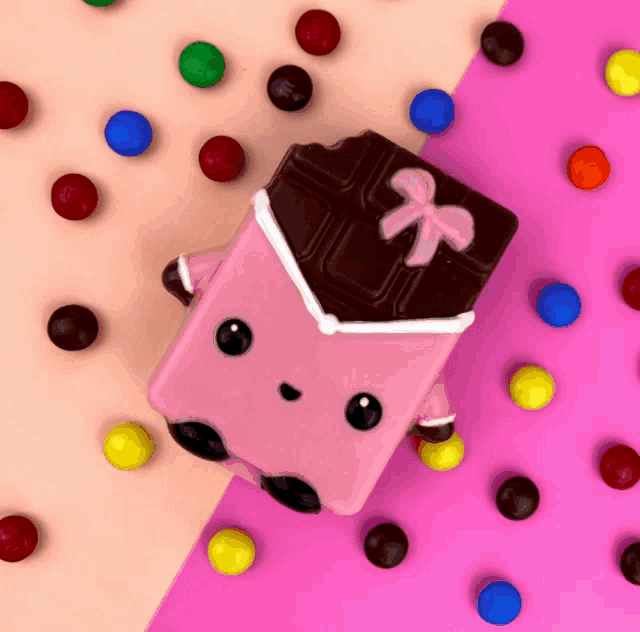 a pink chocolate bar with a bow on it is surrounded by m & m 's