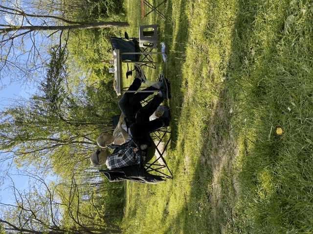 a man sits in a folding chair in a grassy area