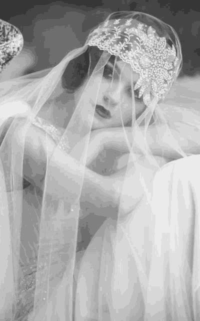 a black and white photo of a woman wearing a veil and a headpiece