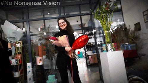 a woman holding a red heart shaped balloon and a bouquet of flowers in front of a sign that says no nonsense