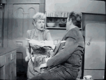 a man and a woman are sitting in a kitchen talking to each other in a black and white photo .