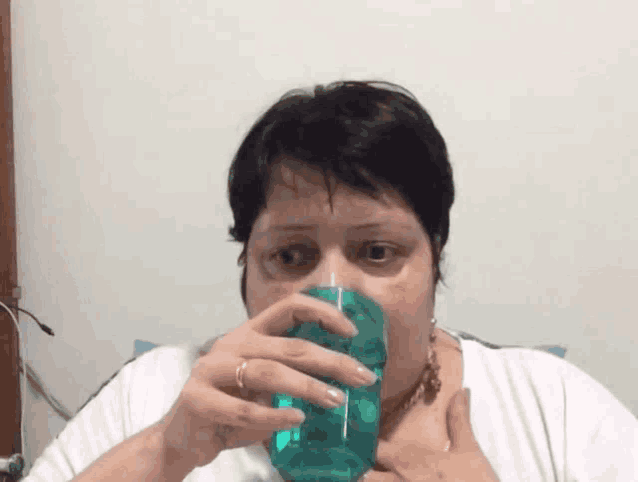 a woman is drinking from a green cup