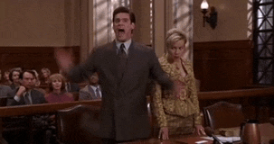 a man in a suit and tie is standing in front of a courtroom .