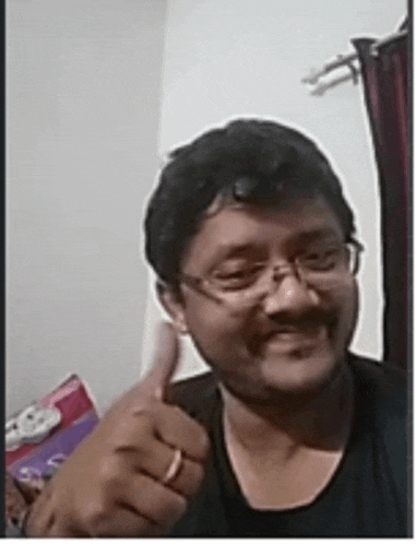 a man wearing glasses is giving a thumbs up sign .