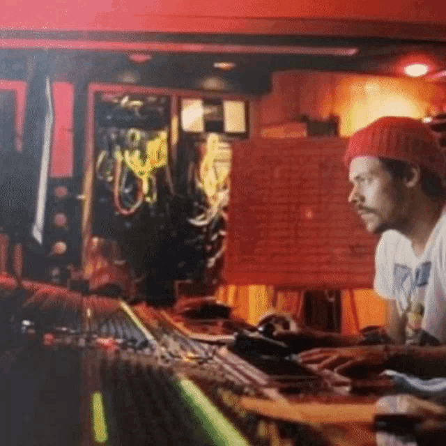 a man wearing a red beanie is sitting at a desk