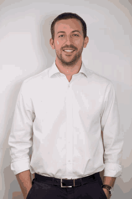 a man wearing a white shirt and black pants is smiling for the camera