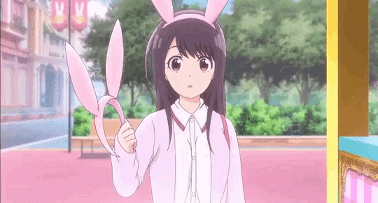 a girl wearing bunny ears is holding a pair of scissors in her hand .