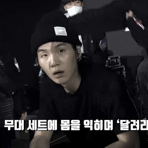 a man wearing a black beanie and a black t-shirt with korean writing