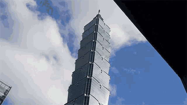 a tall building with a blue sky and clouds in the background