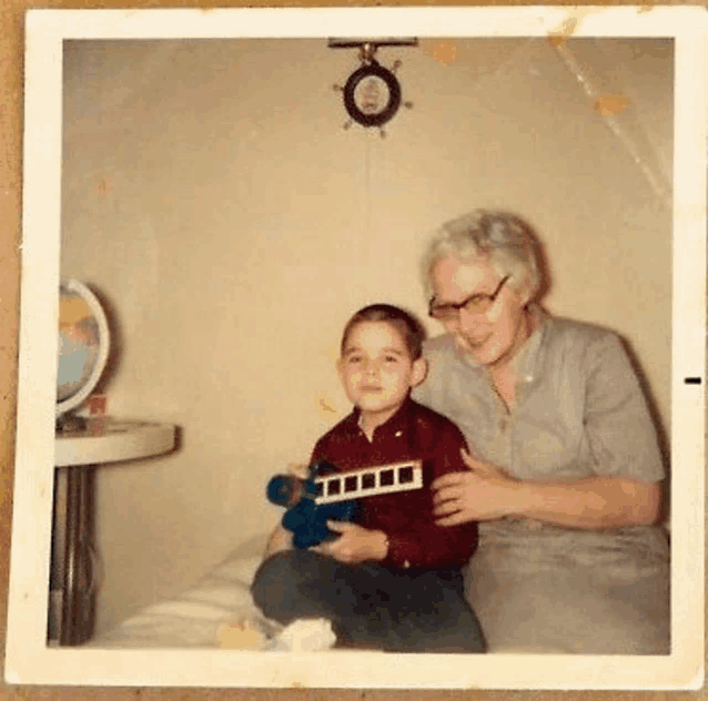 a woman is sitting next to a young boy holding a toy .