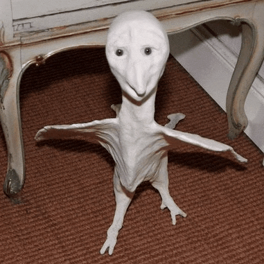 a white statue of a bird is sitting on a brown carpet next to a white table .