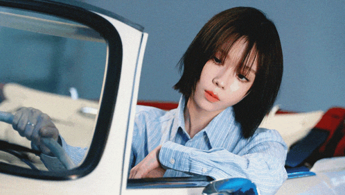 a woman in a blue striped shirt is sitting in a white car