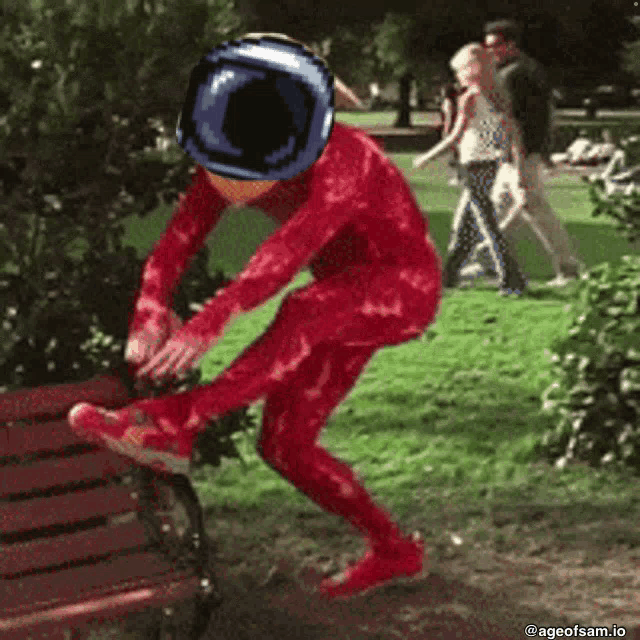 a person in a red jumpsuit is jumping off a bench in a park .