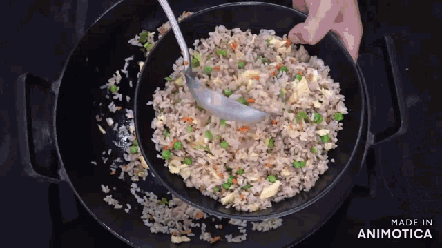 a bowl of rice and vegetables is being stirred with a ladle and the words made in animotica are on the bottom