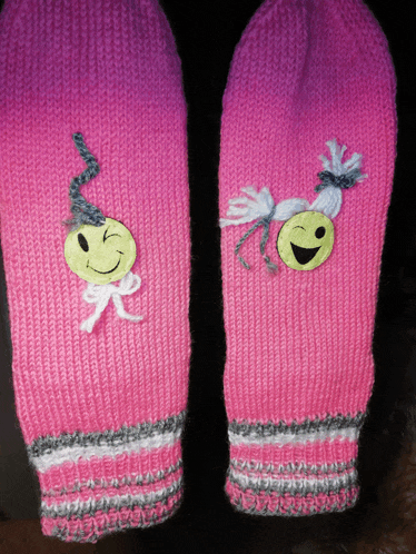 a pair of pink mittens with a yellow smiley face on them