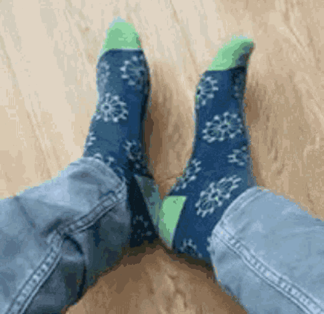 a person wearing blue and green socks with snowflakes on them .