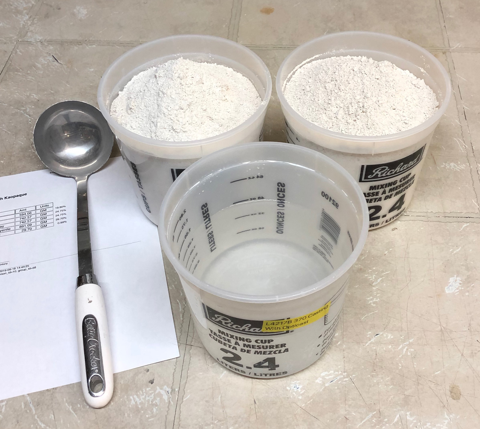 Two almost-full containers of clay powder, one half full of water