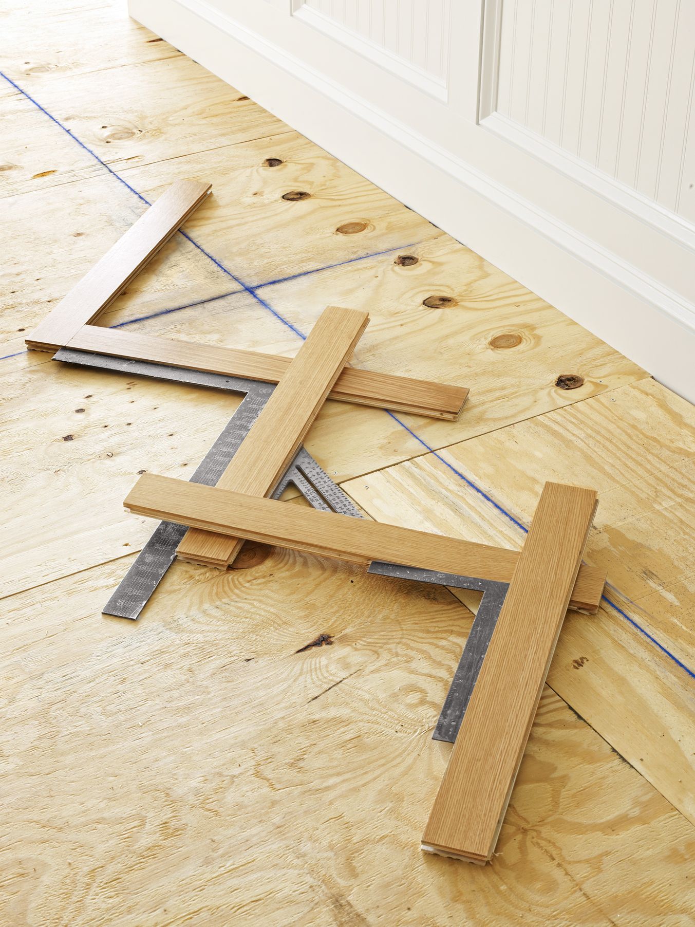 Wood pieces are placed in the herringbone pattern and measured with squares so that they can be cut to fit the floor.