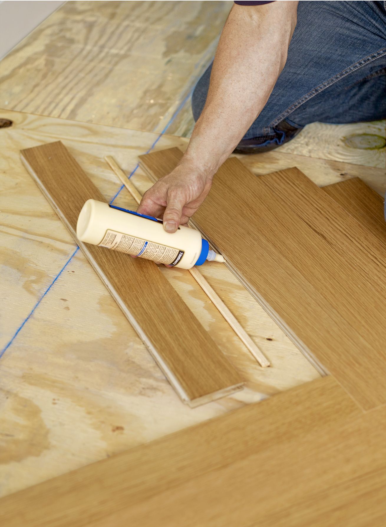 A person backfills the herringbone floor pattern where the blank had been.