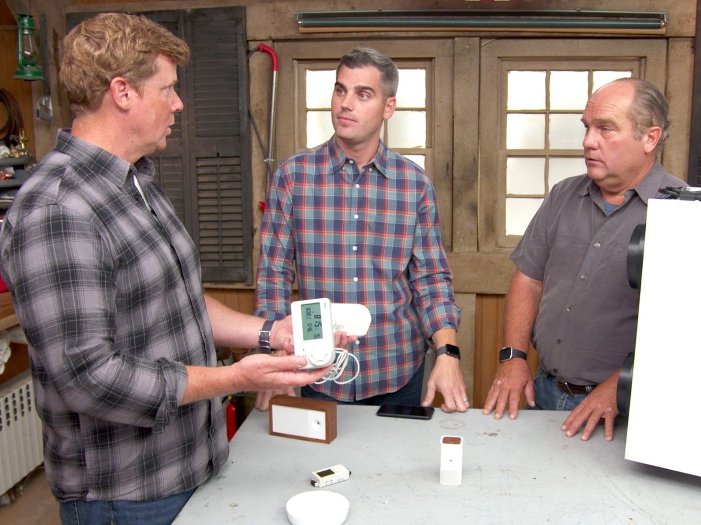 3 Men looking at an indoor air quality monitor.