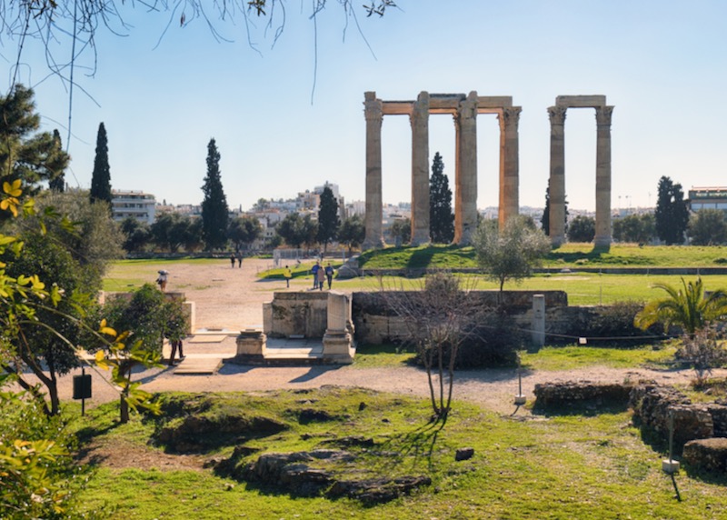 View across a grassy field to the pillars of an ancient ruined temple