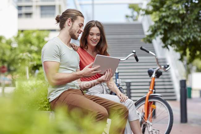 Paar sitzt mit digitalem Tablet auf Hauswand. — Stockfoto