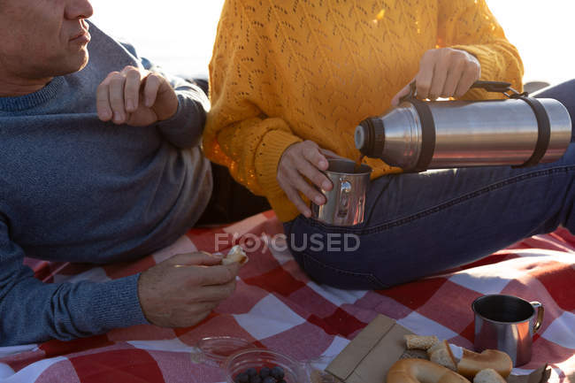 Nahaufnahme eines erwachsenen kaukasischen Paares, das an einem sonnigen Tag die freie Zeit entspannt am Strand genießt und Kaffee trinkt — Stockfoto