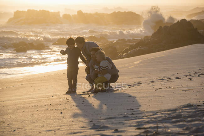 Glückliche Familie mit Spaß am Strand bei Sonnenuntergang — Stockfoto