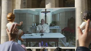 People watch the Pope’s Sunday blessing on a screen on St. Peter's Square at the Vatican, 22 December, 2024