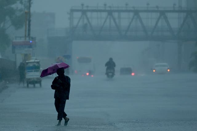 <p>People commute along a street amid heavy rains ahead of a cyclonic storm in Chenna</p>