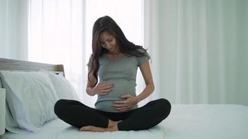 Pregnant Woman Sitting on Bed and Touching Belly in Morning video