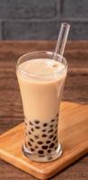 Delicious bubble milk tea with straw in drinking glass on wooden table background, concept of reduce plastic to go in Taiwan, close up, copy space photo