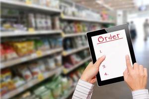 Man using ipad while shopping in supermarket photo