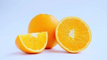 Zoom in to cut in half and slice a ripe orange fruit with golden yellow peel. Isolated on white background with shadow. video