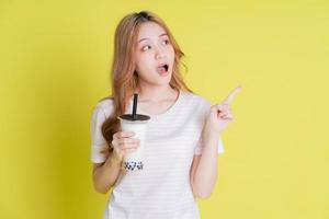 Image of young Asian girl drinking milk tea on yellow background photo